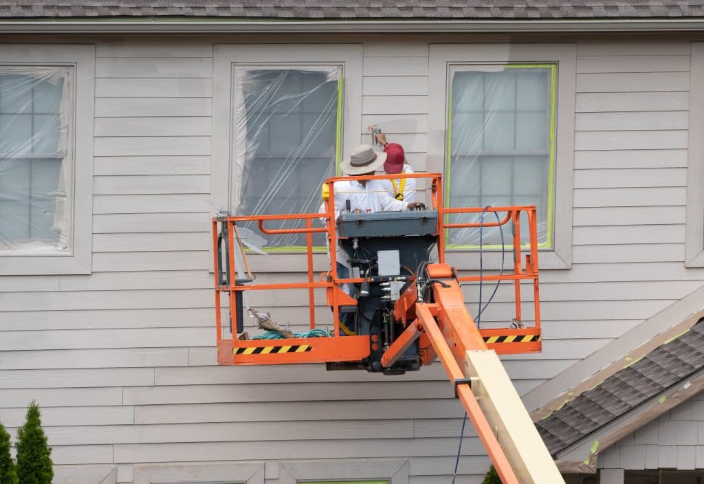 Home exterior being painted by two men